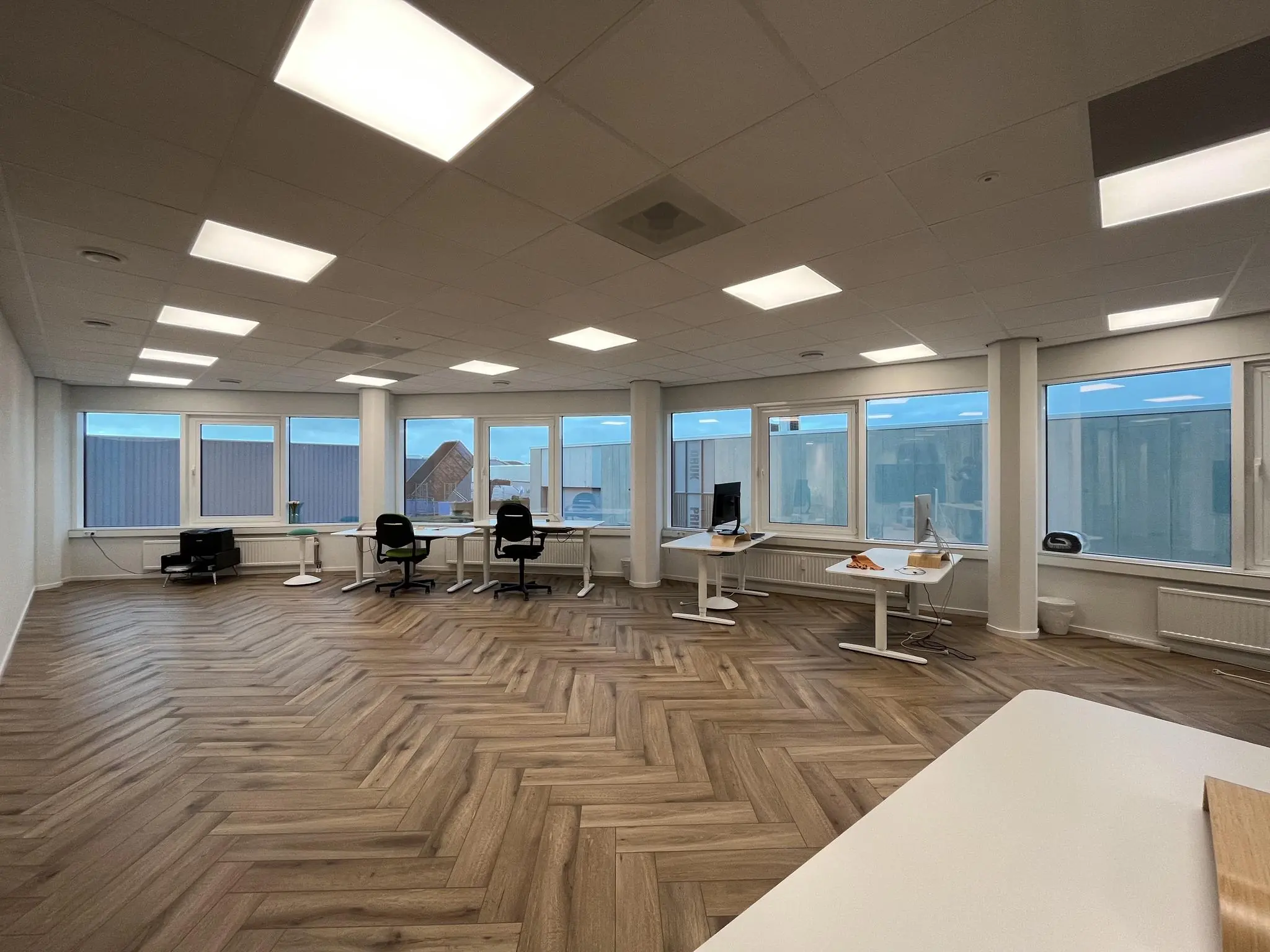 Ruim en modern kantoor aan de Lange Dreef met houten visgraatvloer, grote ramen en zit-sta bureaus.